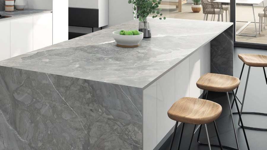 Isla de cocina de porcelánico gris con vetas blancas, con taburetes de madera