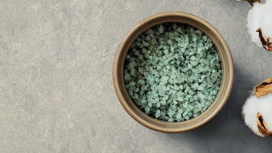Superficie de porcelánico gris verdoso de aspecto piedra con un cuenco de sal y una rama de algodón