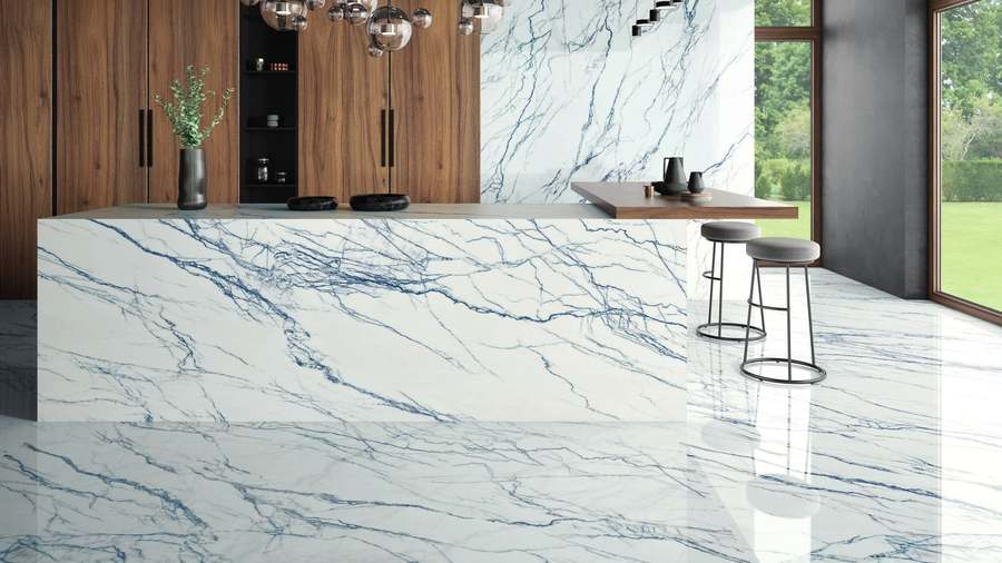 Salón y cocina con suelo y pared revestidos de porcelánico blanco con vetas azules en piezas muy grandes