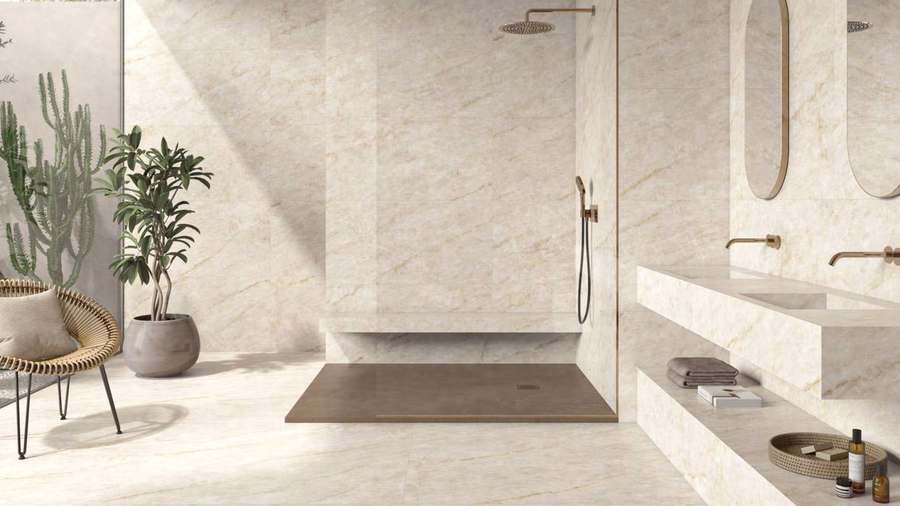 Baño con ducha a ras de suelo, doble lavabo y suelo y paredes de porcelánico color crema con veta de mármol