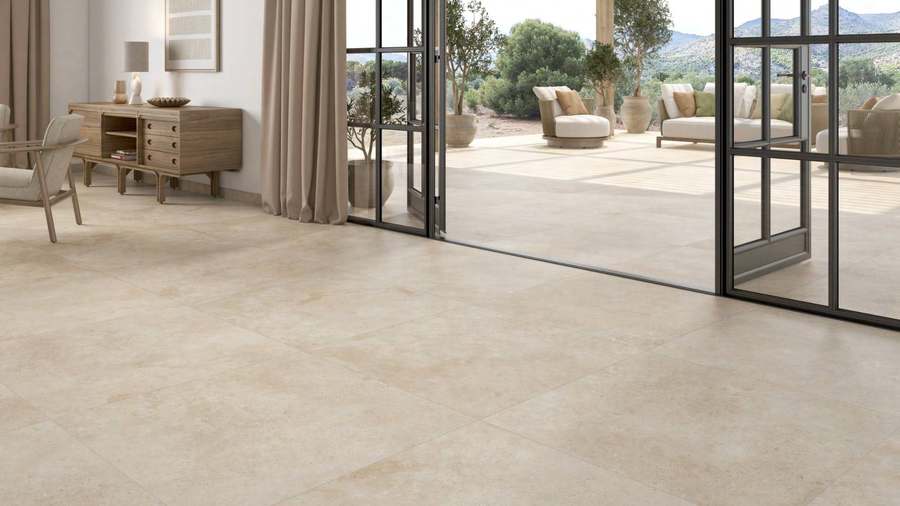 Salón con suelo de porcelánico beige que continúa por unas puertas abiertas hasta una terraza