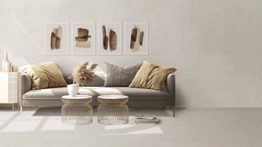 Salón con sofá gris y suelo y pared de porcelánico claro de aspecto cemento