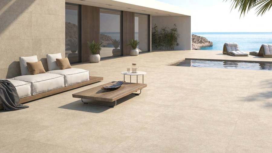 Terraza amplia junto a una piscina con suelo de porcelánico beige de gran formato y aspecto piedra