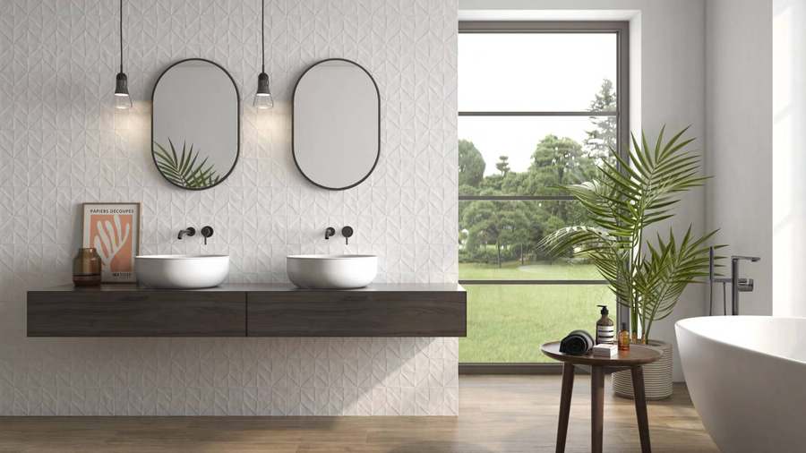 Baño con dos lavabos sobre encimera de madera, pared blanca decorada y bañera exenta junto a un ventanal