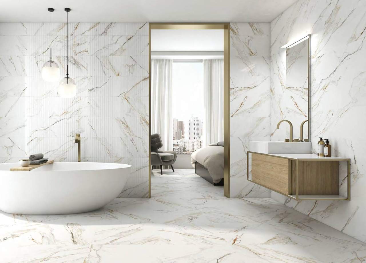 Baño con bañera exenta, paredes y suelo de porcelánico blanco con vetas grises y doradas