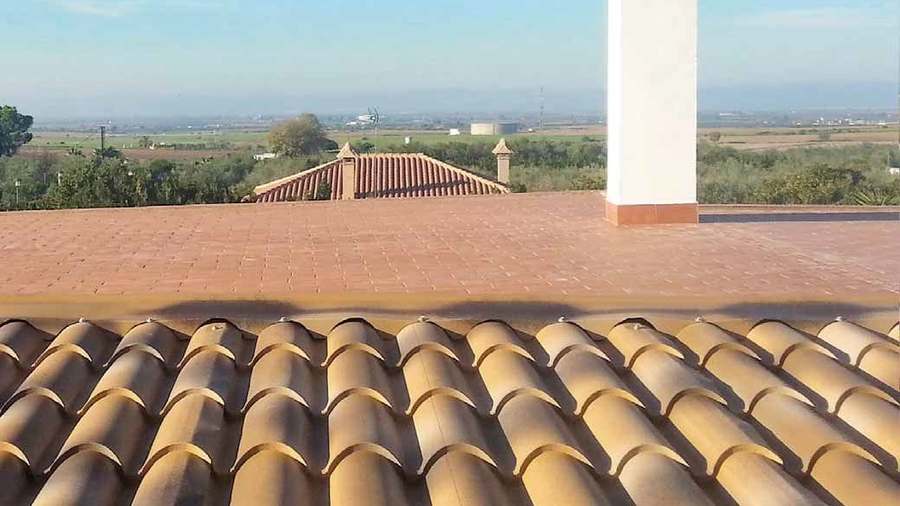 Cubierta de panel sándwich con perfil de teja en tono arena, con campo abierto al fondo